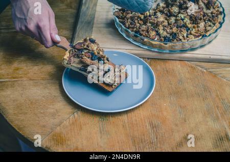 Un pezzo di dolce con noci, mele su un piatto blu Foto Stock