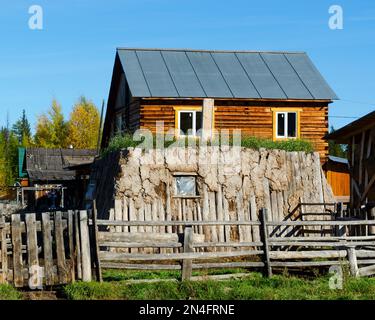 La stanza per il khoton del bestiame, fatta di sterco della mucca e di legno, overgrown con erba si trova su un terreno con una casa fatta di pino nel nord di Yakutia. Foto Stock