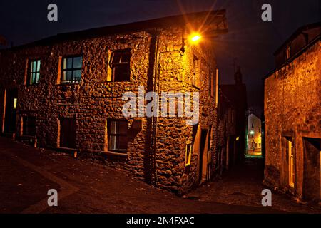 Street scene in Settle, una città mercato nel Yorkshire Dales, visto di notte sotto l'illuminazione stradale vicino a Bowskills Yard. Foto Stock