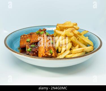 Un piatto gourmet di costolette di maiale gourmet e patatine fritte isolate su uno sfondo bianco Foto Stock