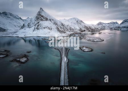Veduta aerea dei paesaggi invernali, delle montagne innevate e della strada ghiacciata nelle isole Lofoten in Norvegia Foto Stock