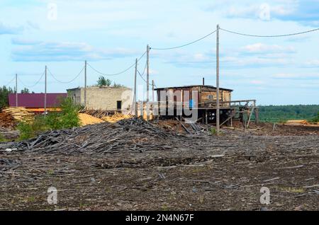 Tavole abbandonate e nuove per la costruzione con segatura vicino ad un campo abbandonato segheria in un villaggio nella Yakutia settentrionale. Foto Stock