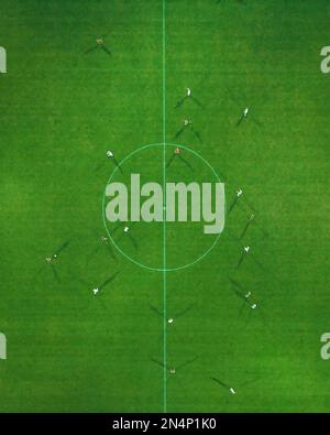 Una vista aerea dall'alto di atleti competitivi che giocano a calcio in un campo erboso - il concetto di sport Foto Stock