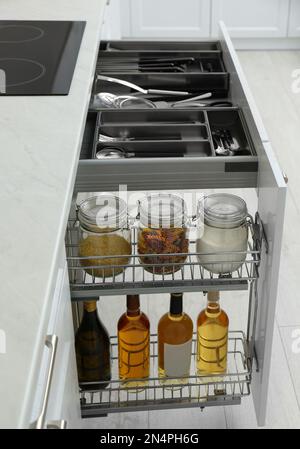 Cassetti aperti con vasetti di cibo, bottiglie di vino e utensili in cucina Foto Stock