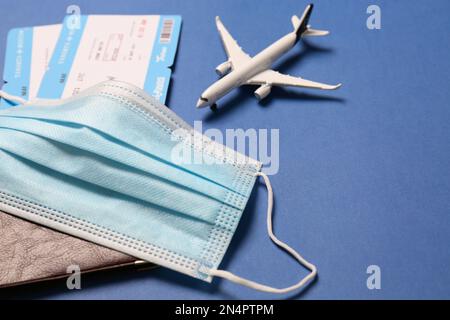 Composizione con passaporto e maschera protettiva su sfondo blu, primo piano. Viaggio durante la quarantena Foto Stock