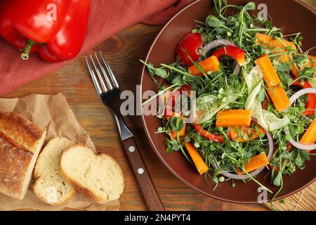 Deliziosa insalata di verdure con microgreens servita su un tavolo di legno, piatto Foto Stock