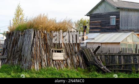 La stanza per il khoton del bestiame, fatta di sterco della mucca e di legno, overgrown con l'erba sta su un terreno con una casa ed una serra nel nord di Yakutia. Foto Stock