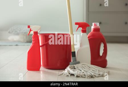 Secchio, spazzolone e diversi prodotti per la pulizia sul pavimento interno Foto Stock