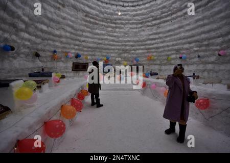 I turisti indiani scattano le loro foto all'interno di un 'Igloo Cafe', un caffè preparato con neve e ghiaccio, il 8 febbraio 2023 a Gulmarg, ad ovest di Srinagar, la capitale estiva del Kashmir, India, amministrato dall'India. Gulmarg, una delle stazioni sciistiche più popolari dell'Asia, di Gulmarg a Jammu e Kashmir. Con un'altezza di 112 metri (40 piedi) e un diametro di 12,8 metri (42 piedi), creatore dell'igloo, ha affermato che era il più grande caffè del mondo del suo genere. Ci sono voluti 20 giorni per completarlo con 25 persone che lavorano giorno e notte, ha detto, aggiungendo che ci sono voluti 1.700 giorni-uomo per completare il progetto. (Foto di Mubash Foto Stock