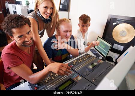 La creazione di un successo richiede tempo... quattro giovani ingegneri audio che lavorano su una scrivania di mixaggio. Foto Stock