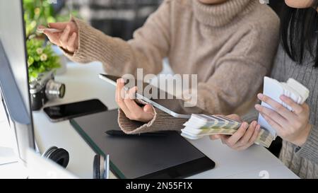 Due designer grafici femminili asiatici professionali e creativi che lavorano insieme a un progetto in ufficio, scegliendo il colore dalla tavolozza dei colori per loro Foto Stock