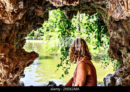 Donna bionda dai capelli ricci seduta guardando il lago del Parque del Retiro a Madrid, Spagna Foto Stock