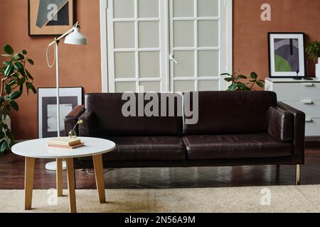 Immagine orizzontale del moderno soggiorno con comodo divano in pelle al centro della stanza e tavolino da caffè Foto Stock