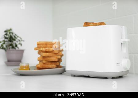 Tostapane bianco con fette di pane e una tazza di caffè sul tavolo, primo  piano Foto stock - Alamy