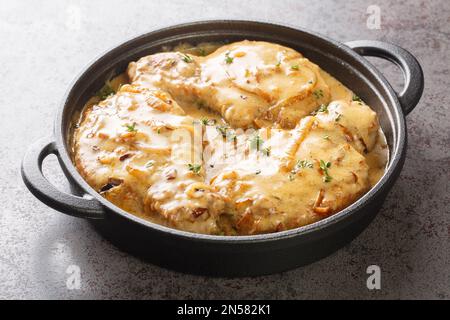 Braciole di maiale speziate fritte e poi brasate in cremoso closeup con sugo di cipolla sulla padella sul tavolo. Orizzontale Foto Stock