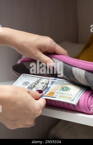 l'uomo nasconde i dollari nell'armadio con i vestiti. donna che nasconde i soldi nei vestiti. stash con dollari. Foto Stock