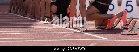 Gruppo di atleti maschi su blocchi di partenza. Mani sulla linea di partenza. Atleti alla linea di partenza sprint in pista e sul campo Foto Stock