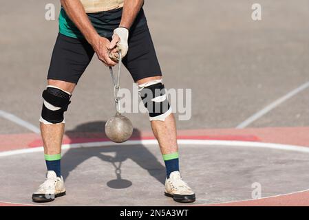 Un atleta che gareggia nell'evento del tiro del martello, un atleta che esegue un tiro del martello nello stadio Foto Stock