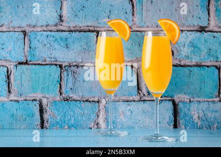 Rinfrescanti cocktail Mimosa all'arancia con champagne su sfondo luminoso. Foto Stock