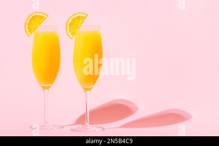 Rinfrescanti cocktail Mimosa all'arancia con champagne su sfondo luminoso. Foto Stock