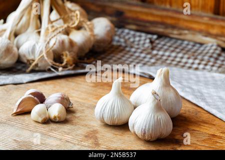 Bulbo d'aglio su tavolo rustico in legno. Spicchi d'aglio appena sbucciati. Foto Stock
