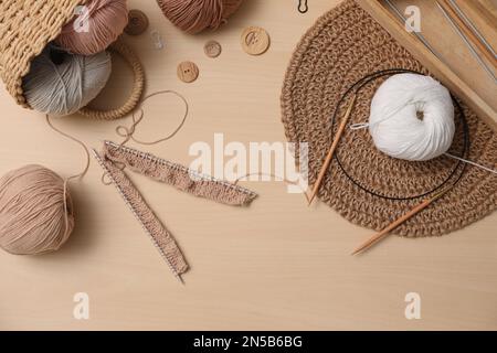 Composizione piana con fili e accessori per la lavorazione su tavolo in legno. Hobby coinvolgente Foto Stock