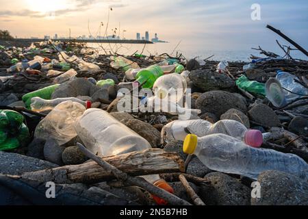 Inquinamento di plastica della spiaggia. Bottiglie di plastica e altri rifiuti sulla spiaggia di pietra marina nella città di Batumi, Georgia. Concetto ecologico. Foto Stock