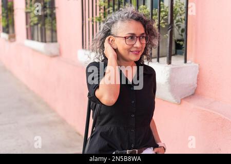 Donna latina moderna che cammina per la strada Foto Stock