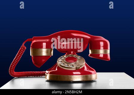 Telefono a filo rosso vintage sul tavolo su sfondo blu Foto Stock