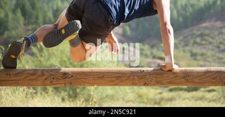 Partecipante a un percorso ad ostacoli che corre, saltare sopra un ostacolo di legno Foto Stock