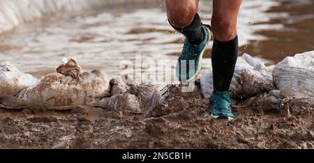 Il partecipante ad una corsa ad ostacoli corre fuori da un ostacolo d'acqua, concetto di durezza e sforzo Foto Stock