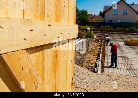 Porta aperta, fatta di tavole di legno inchiodate con chiodi metallici, ingresso del sito, fondazione di edifici residenziali è in costruzione in background. Foto Stock