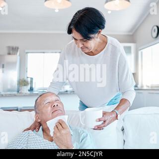 Salute, l'uomo anziano con influenza e la donna anziana con la tazza, il pensionamento e l'operatore sanitario in soggiorno. Allergie, uomini maturi sul divano e donne anziane dentro Foto Stock