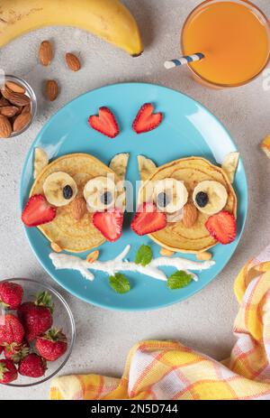 Frittelle a forma di gufo con fragole, banane e mandorle, una colazione creativa per bambini o San Valentino Foto Stock