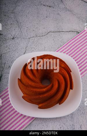 Torta rotonda di mandorle e farina di riso sul tovagliolo da tè a strisce e tavolo di marmo. Foto Stock