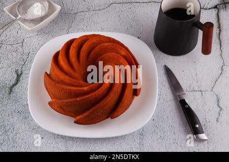 Torta rotonda di mandorle e farina di riso sul tovagliolo da tè a strisce e tavolo di marmo. Colazione con tazza di caffè. Foto Stock