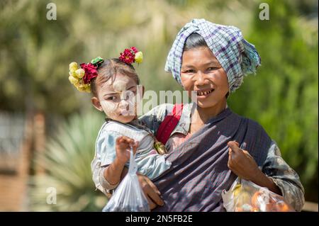 Betel birmano masticare donna con bambino a Bagan. La pittura facciale con colore bianco-giallo chiamata Thanaka è un cosmetic popolare in Myanmar. Foto Stock