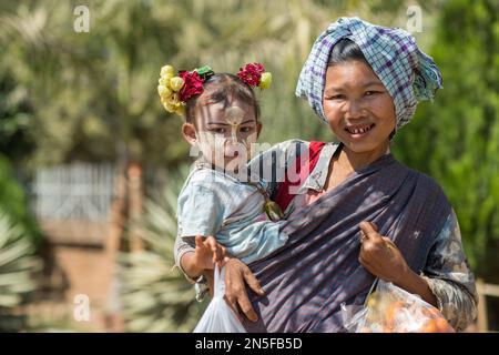 Betel birmano masticare donna con bambino a Bagan. La pittura facciale con colore bianco-giallo chiamata Thanaka è un cosmetic popolare in Myanmar. Foto Stock