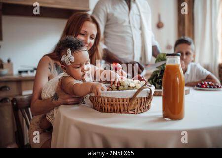 La famiglia di razza mista con il bambino bianco figlia swarthy swarthy passare il tempo insieme mattina. L'uomo afroamericano con la sua moglie giusta skinned i capretti godono healt Foto Stock