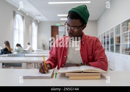 Giovane scienziato afro-americano di talento che indossa gli occhiali che studiano in biblioteca. Concetto di istruzione Foto Stock