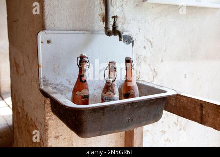 vecchie bottiglie di birra in piedi in un lavabo Foto Stock