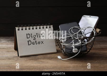 Cestino con diversi gadget e parole DETOX DIGITALE su tavolo di legno Foto Stock