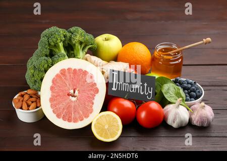 Scheda con parola immunità e prodotti freschi su tavola in legno Foto Stock