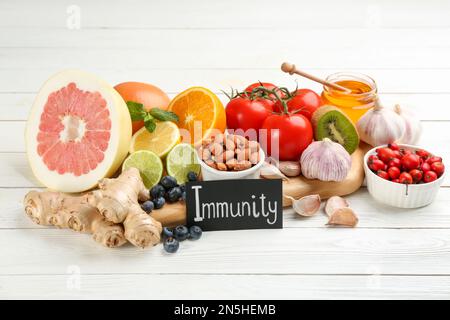 Scheda con parola immunità e prodotti freschi su tavolo di legno bianco Foto Stock