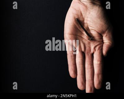 La mano con un vecchio chiodo arrugginito simboleggia la crocifissione di Gesù. Concetto di Pasqua con testo libero spazio Foto Stock