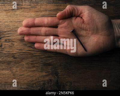 La mano con un vecchio chiodo arrugginito simboleggia la crocifissione di Gesù. Concetto di Pasqua con testo libero spazio Foto Stock