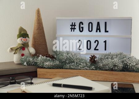 Light box con hashtag Goal 2021 vicino al notebook sul tavolo. Obiettivi per il nuovo anno Foto Stock