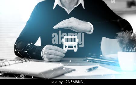 Assicuratore che protegge un autobus di carta con la mano; effetto luce Foto Stock