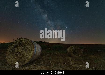 Vista notturna con la via lattea di un campo di balle di fieno, la Sicilia Foto Stock