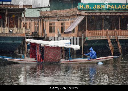 Un barcaiolo visto indossare un impermeabile rema la sua barca attraverso il lago dal durante la pioggia a Srinagar. La maggior parte delle parti della valle del Kashmir ha ricevuto le precipitazioni, mentre i tratti più alti hanno ricevuto le nevicate fresche, abbassando i livelli di mercurio. Il tempo meteorologico ha previsto il tempo umido fino a febbraio 11. Foto Stock